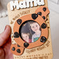 A hand holding a fridge photo magnet designed for Mother's Day, featuring a wooden frame with a cut-out shape of a cookie and the text 'MAMA, TOTALLY WOULD CRUMBLE WITHOUT YOU'.