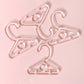 A set of pink plastic hangers designed for earrings, with a heart shape at the top hook.