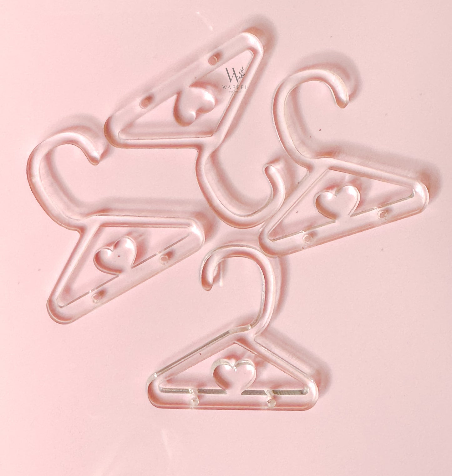 A set of pink plastic hangers designed for earrings, with a heart shape at the top hook.