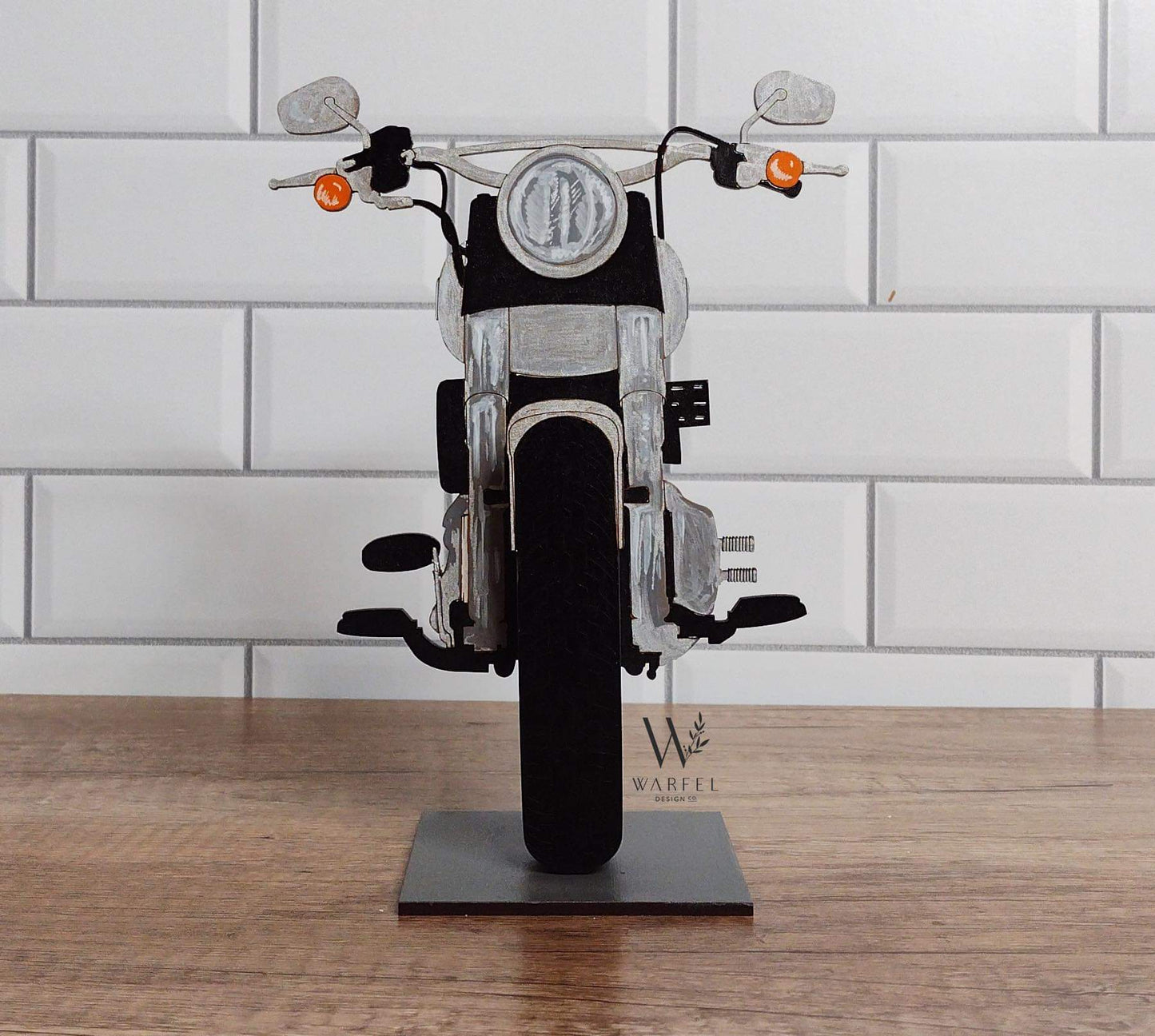 A motorcycle-shaped eyeglasses holder, with a black seat and silver metallic parts, displayed on a stand.